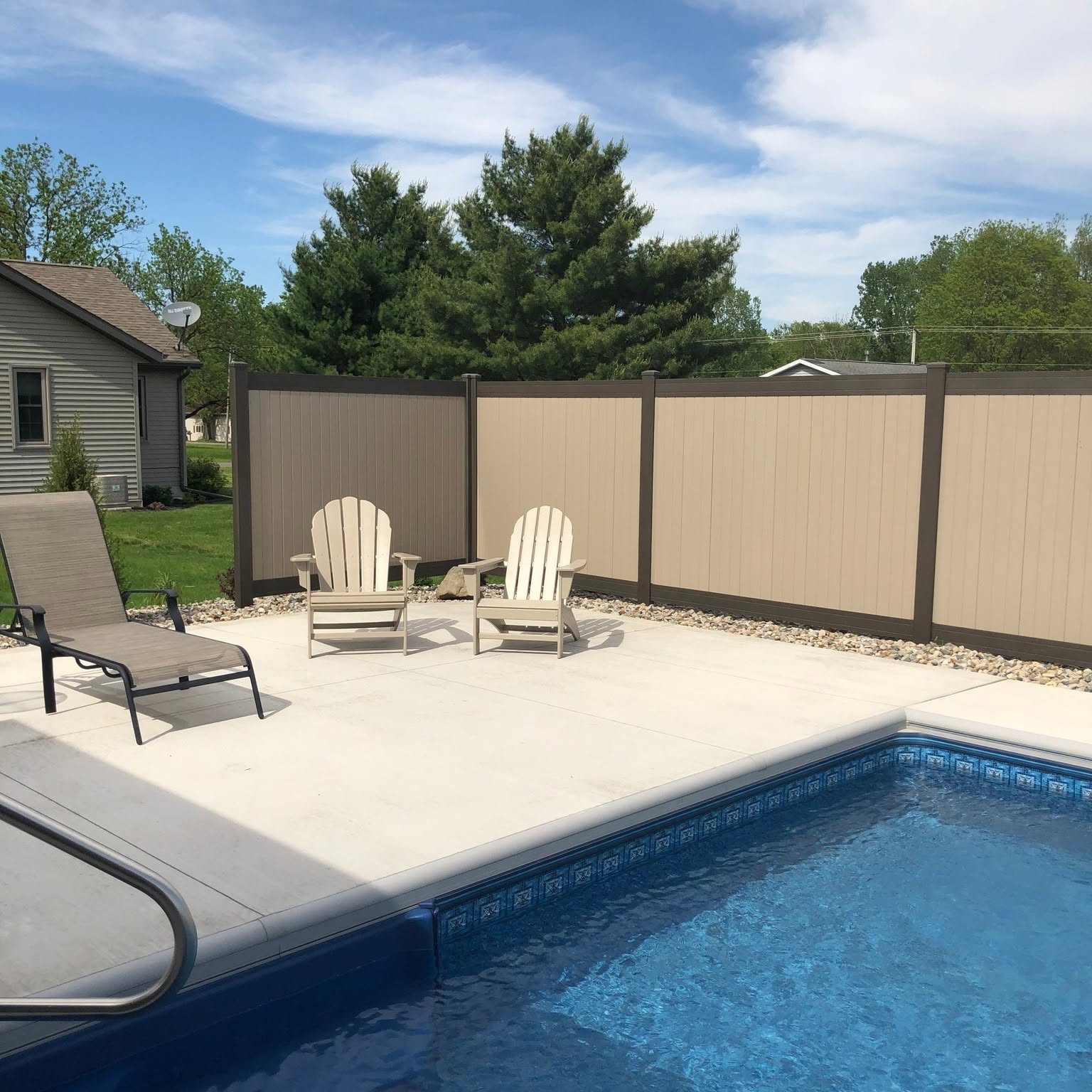 Tan vinyl privacy fence surrounding an in-ground swimming pool and patio