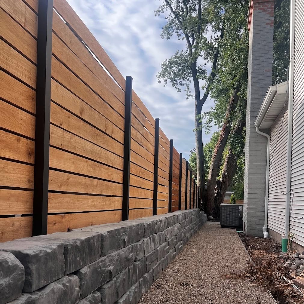 Horizontal cedar fence with black steel posts set on a stone retaining wall